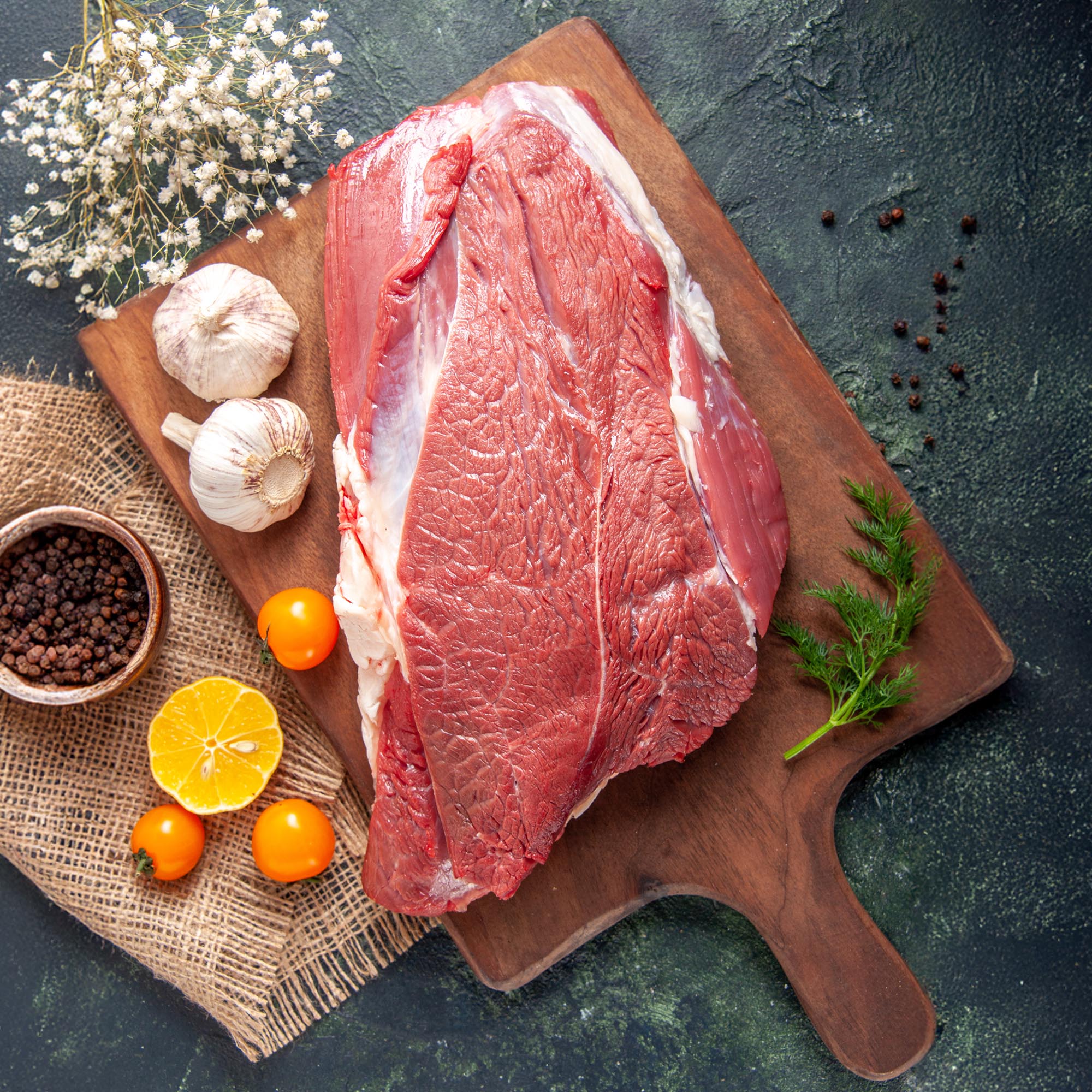 vertical view fresh raw red meats green garlics brown wooden cutting board tomatoes pepper nude color towel knife dark color background copy